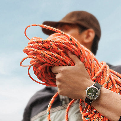 Person holding a large coil of orange rope with a blurred background