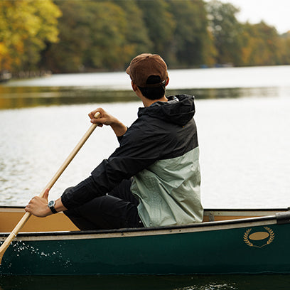 Person paddling a canoe on a lake with trees in the background