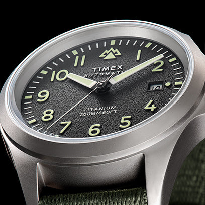 Timex Expedition watch with metallic case and green strap on a black background