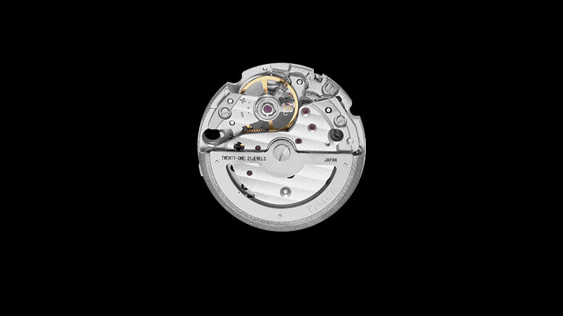 Detailed view of the Timex Marlin® Automatic movement mechanism, showcasing gears, jewels, and rotor engraved with “TWENTY-ONE 21 JEWELS” and “JAPAN.” The precision and craftsmanship of the mechanical engine are on full display against a dark background.