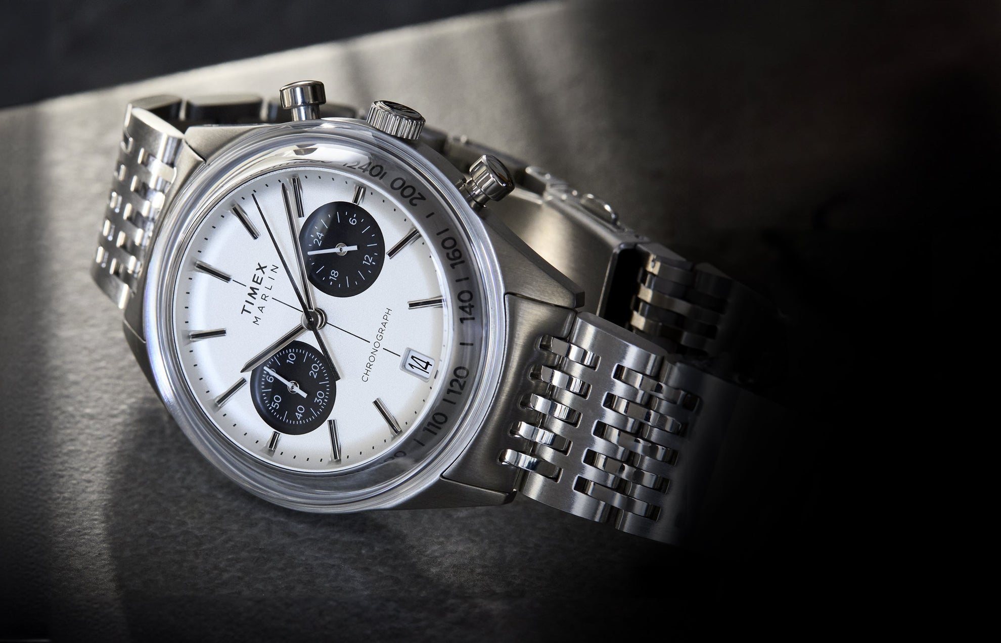 A close-up angled view of the Timex Marlin® Jet Quartz Chronograph. The watch features a white dial with two black sub-dials, a date window at 4 o’clock, silver-tone case and markers, and a polished stainless steel bracelet.