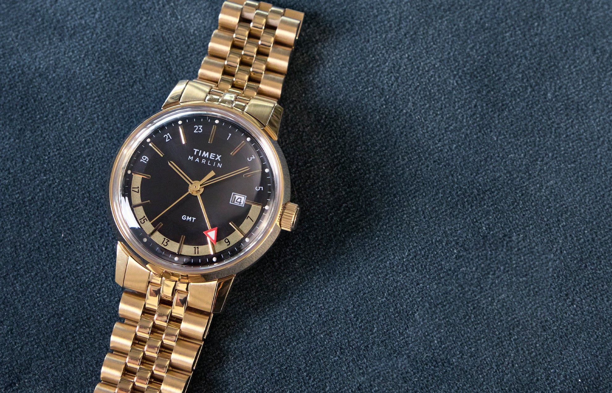 Gold wristwatch with a black face on a dark blue background