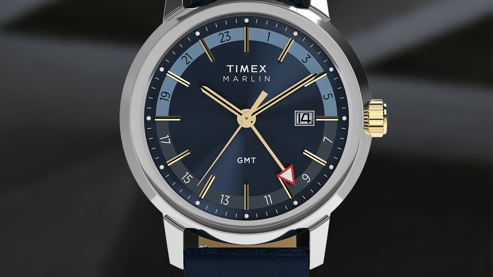 A front-facing render of the Timex Marlin® Quartz GMT with a sunburst navy-blue dial, 24-hour dual-tone inner ring, gold-tone markers, and a date window at 3 o’clock. The case is stainless steel with a gold-tone crown.