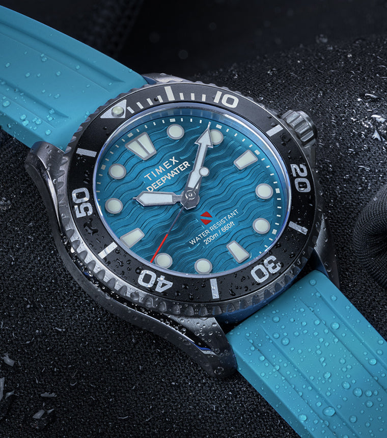 Timex Deepwater Meridian 200 dive watch with aqua blue strap and dial, resting on a wetsuit with water droplets.