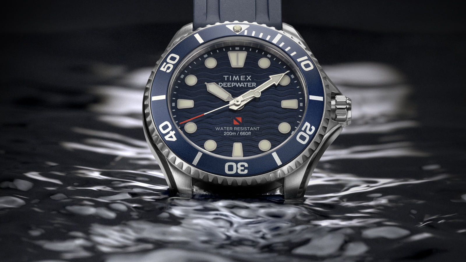 Timex Deepwater Meridian 200 with a blue strap and wave-pattern dial resting on the surface of dark water.
