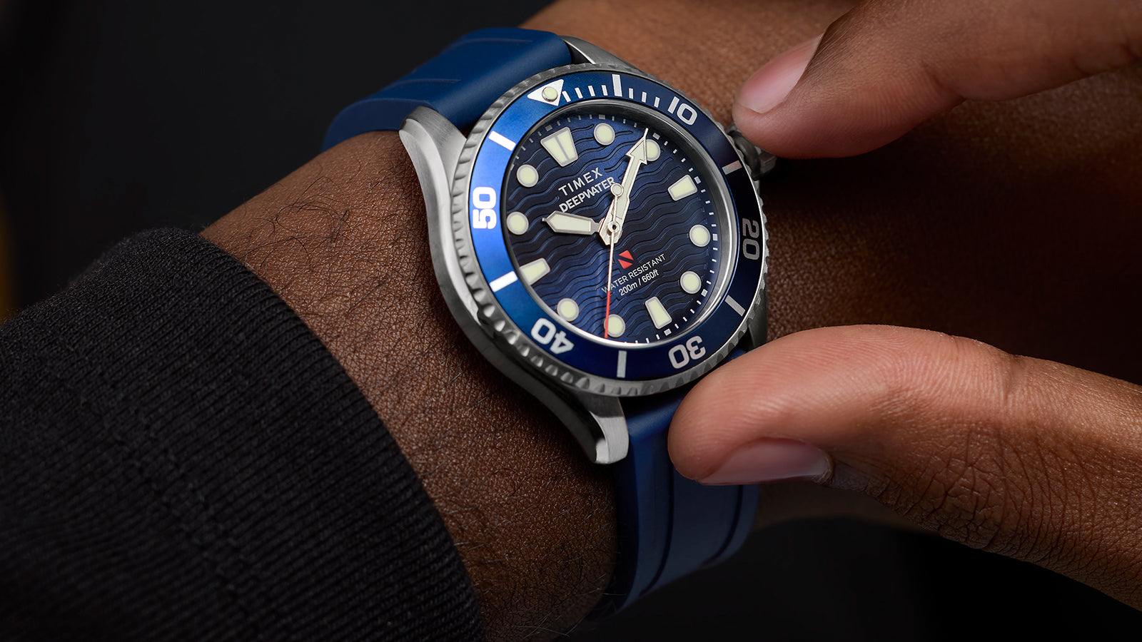 Close-up of a person wearing the Timex Deepwater Meridian 200 dive watch with a blue strap, adjusting the bezel.