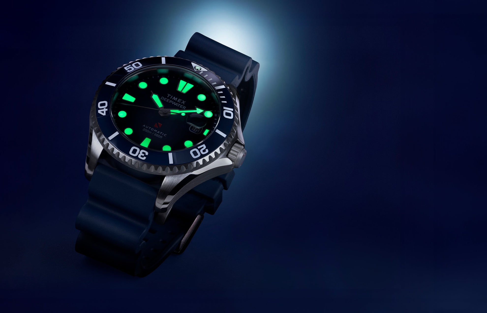 Close-up of the Timex Deepwater Meridian 200 automatic dive watch with luminous markers glowing green against a dark blue background.
