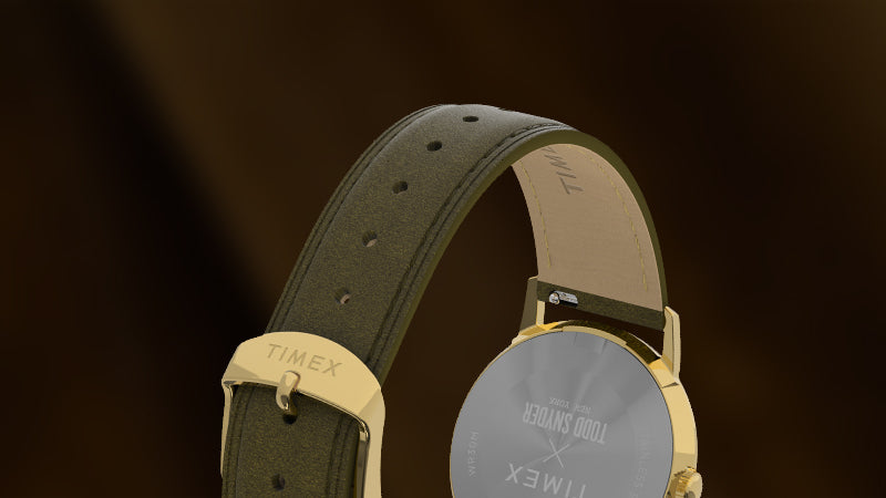 Detail shot of the Timex x Todd Snyder watch's olive leather strap and gold-tone buckle, with "Timex" engraved and the inner strap marked with “Todd Snyder.”