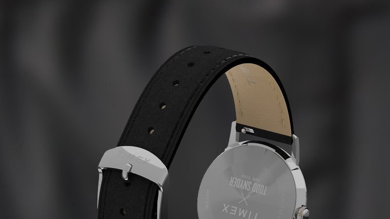 Detailed rear view of the Timex x Todd Snyder watch’s black leather strap and stainless-steel buckle engraved with "Timex", with “Todd Snyder” branding visible on the caseback and underside of the strap.