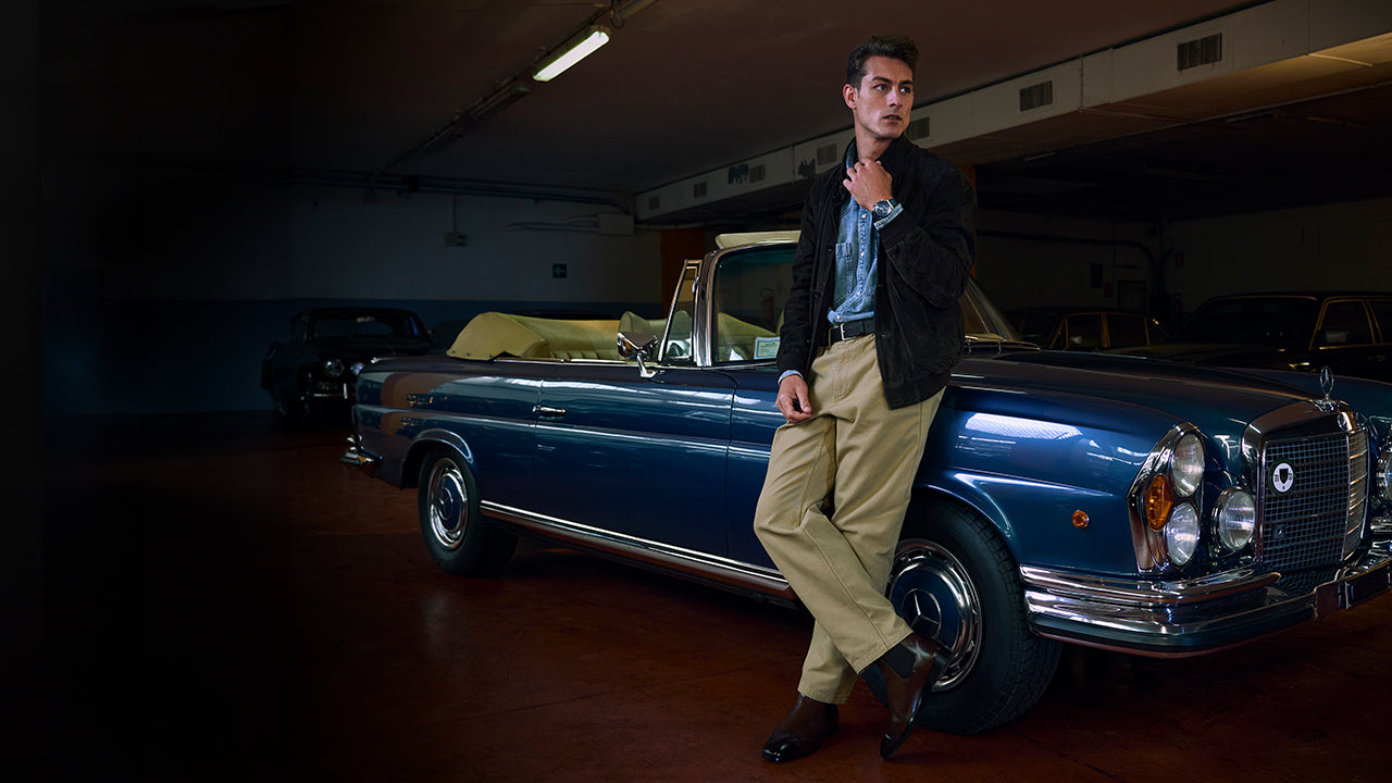 Model leaning on a vintage blue convertible wearing a Q Timex® Chronograph with blue dial and leather strap.