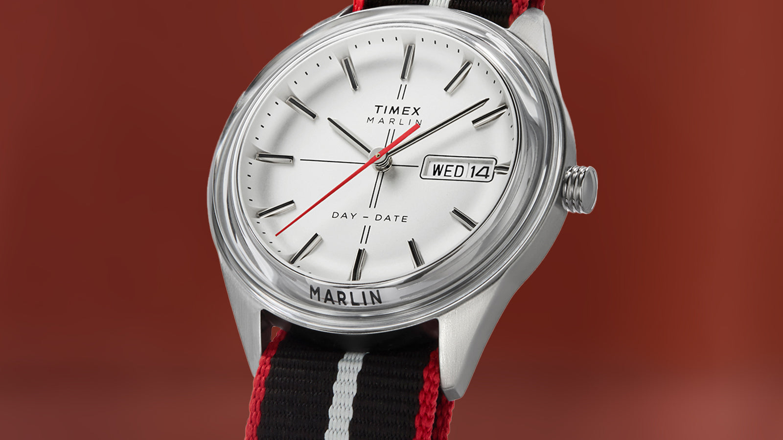 Timex Marlin® Jet Quartz watch against a solid background, featuring a white dial, silver-tone indices, red seconds hand, and day-date window at 3 o’clock.