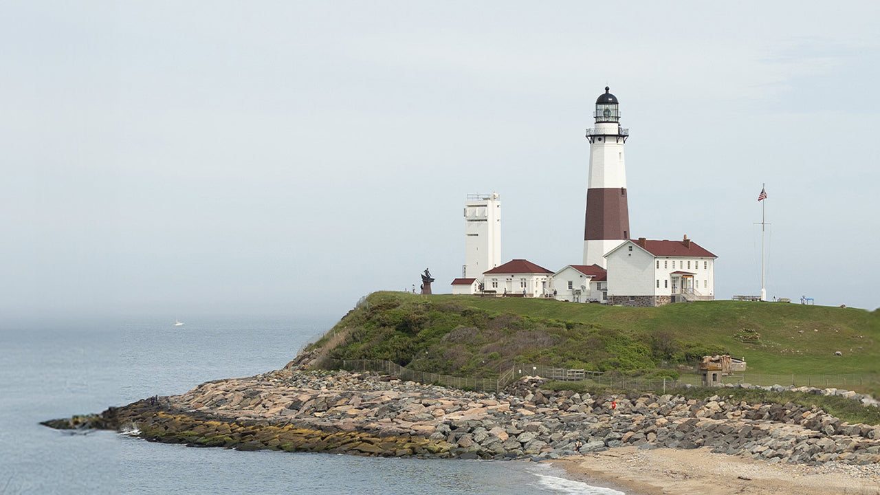 Montauk Point Lighthouse on Long Island, New York, overlooking the rocky shoreline with the ocean in the background.