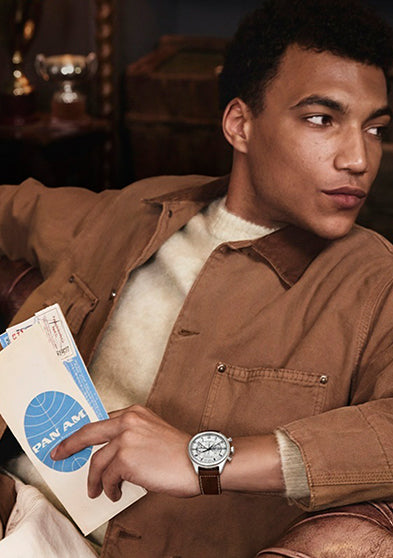 Model wearing the Timex x Pan Am® Waterbury Ace Chronograph while holding vintage Pan Am travel documents, evoking mid-century air travel style.