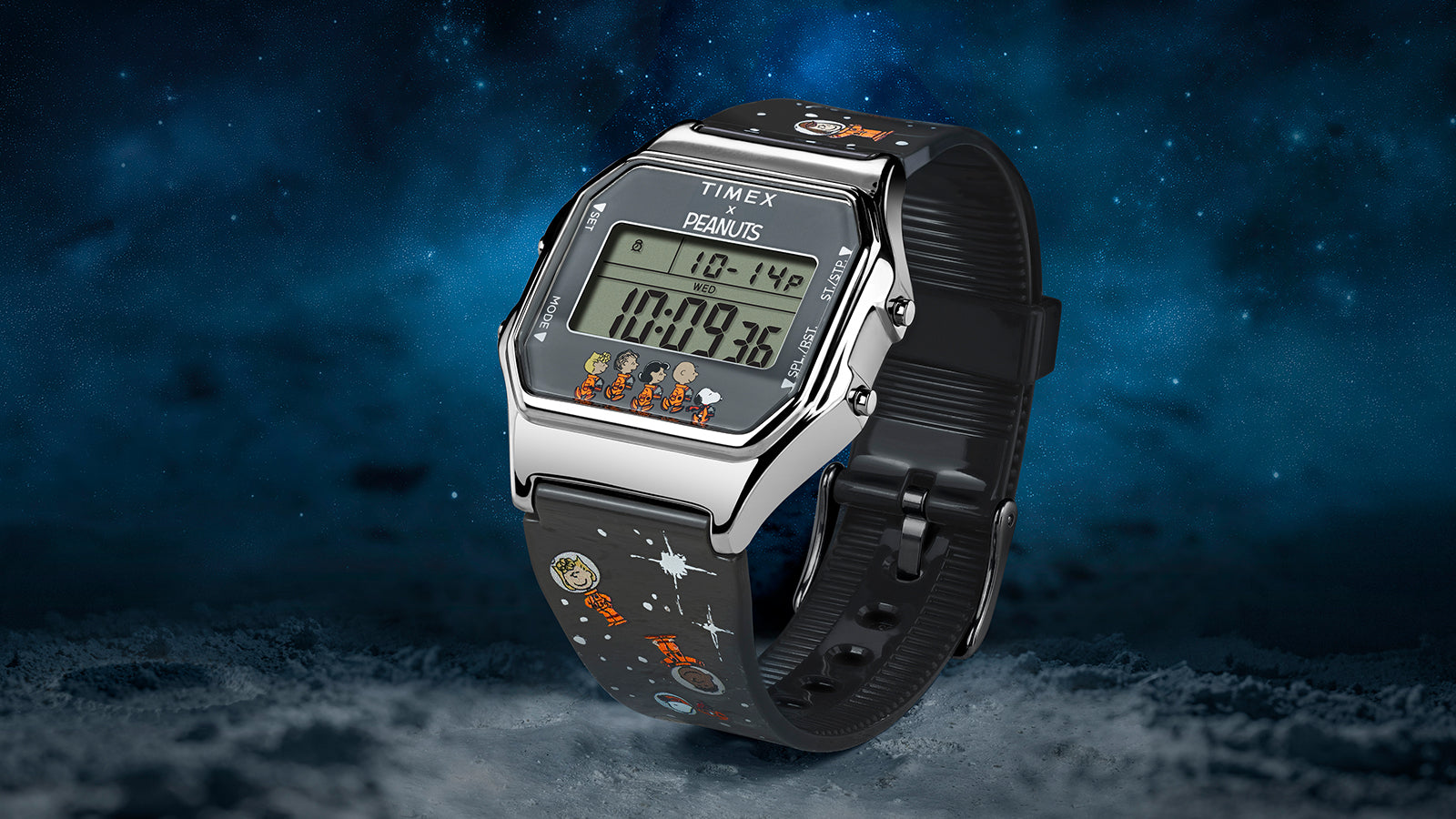 Three-quarter angled view of the Timex x Peanuts® T80 digital watch with a black starry strap featuring Peanuts space illustrations. The watch sits against a moon-like textured surface with a cosmic blue sky in the background.