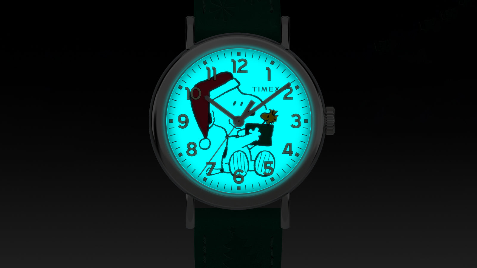Timex x Peanuts® Weekender Holiday Dial watch glowing with blue-green INDIGLO® backlight, illuminating Snoopy in a Santa hat holding a gift for Woodstock on the dial.