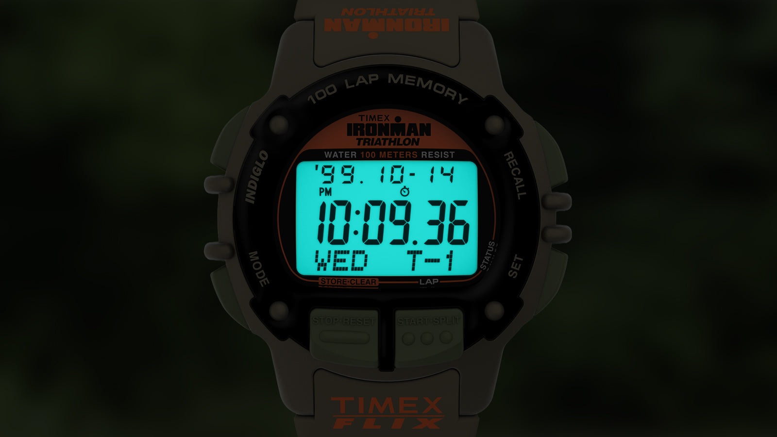 A darkened image of the TIMEX® IRONMAN® Flix x Huckberry showing its signature INDIGLO® backlight illuminating the full digital display in blue-green glow.