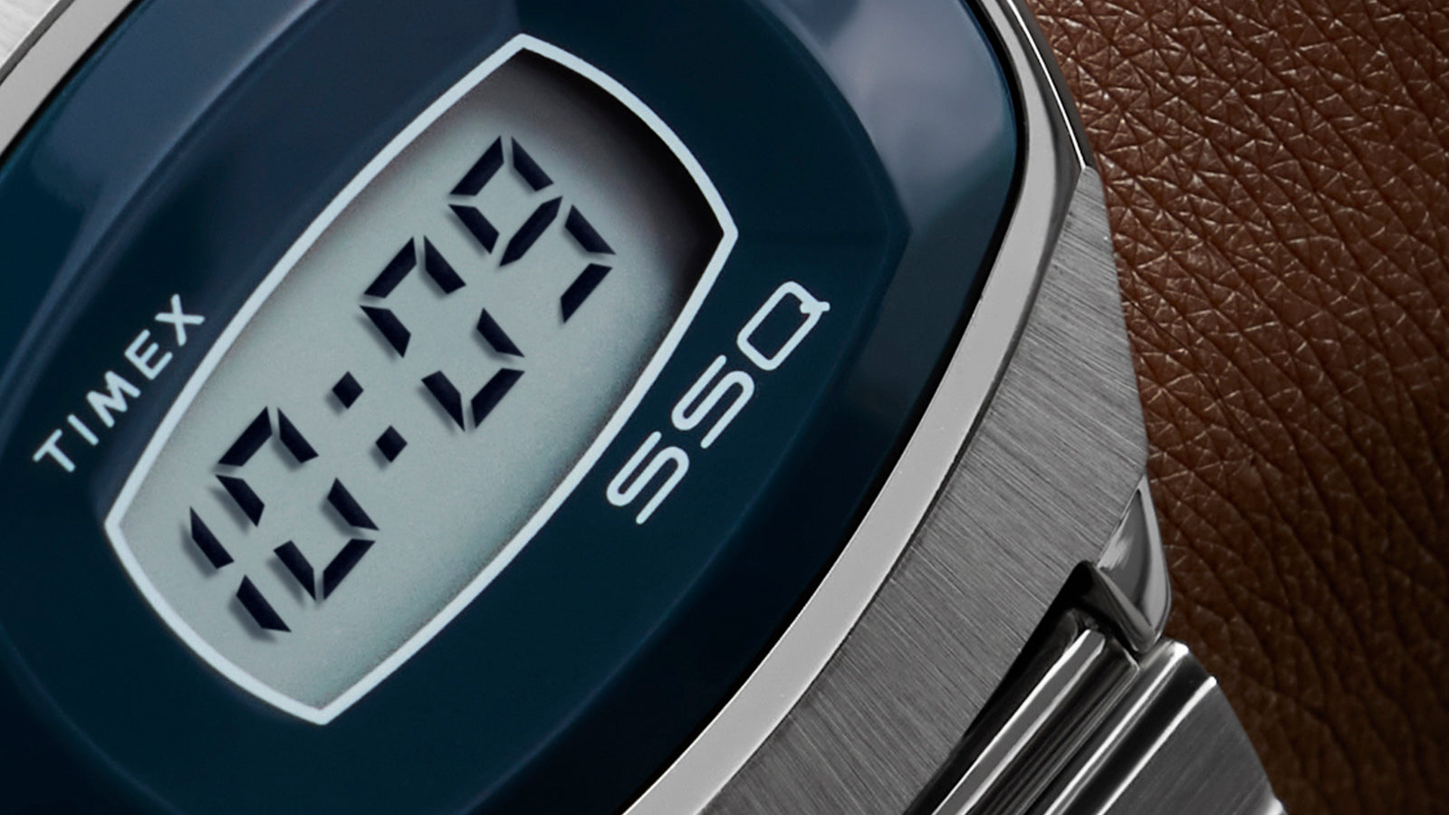 Macro shot of the Q Timex® 1975 SSQ Digital Reissue digital screen highlighting the clean “10:09” LCD numerals, the Timex and SSQ branding, and brushed steel texture.