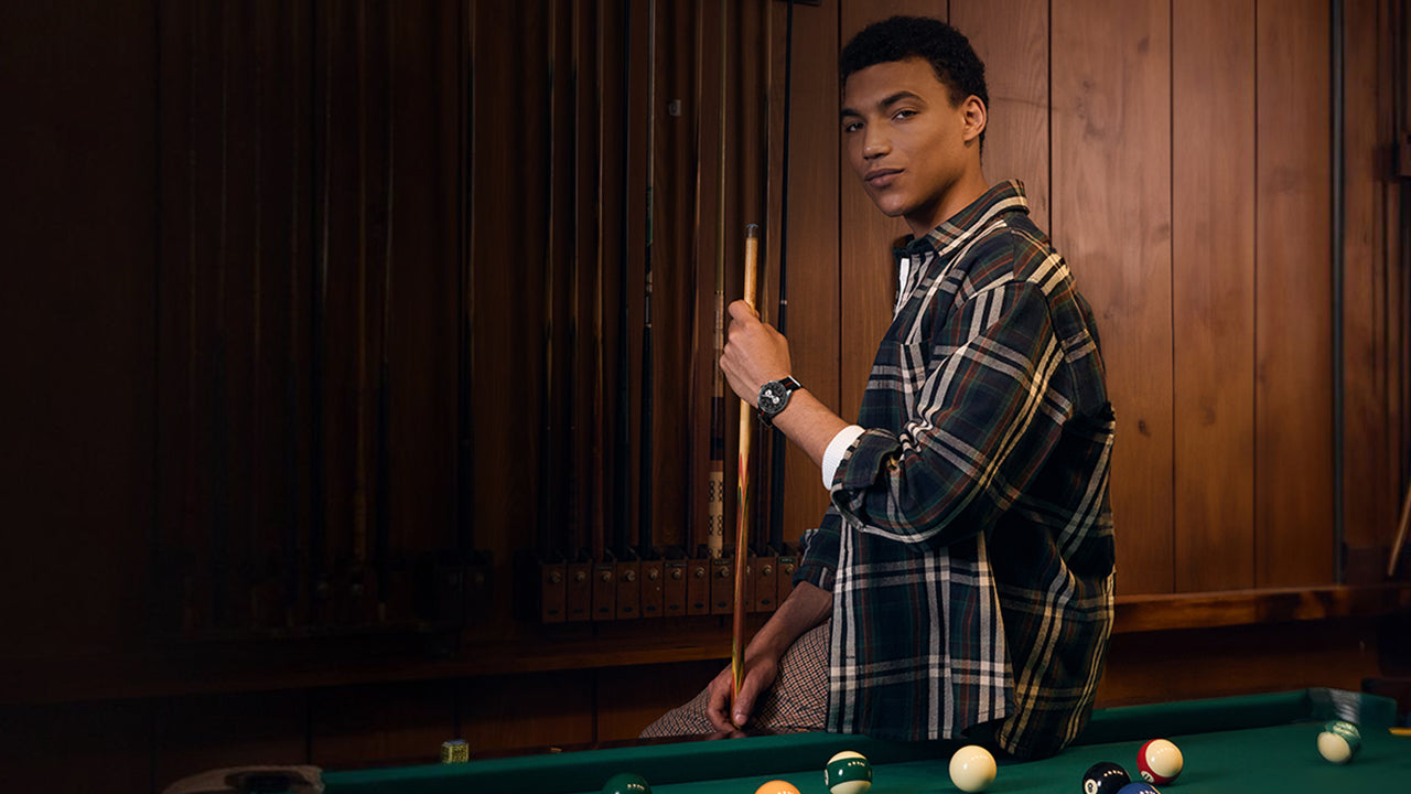 Model wearing the Timex Waterbury Heritage Chronograph while standing by a pool table, dressed in a plaid shirt for a casual and confident look.