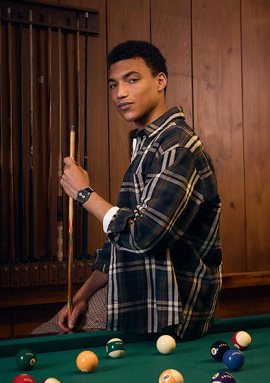 Model wearing the Timex Waterbury Heritage Chronograph while standing by a pool table, dressed in a plaid shirt for a casual and confident look.