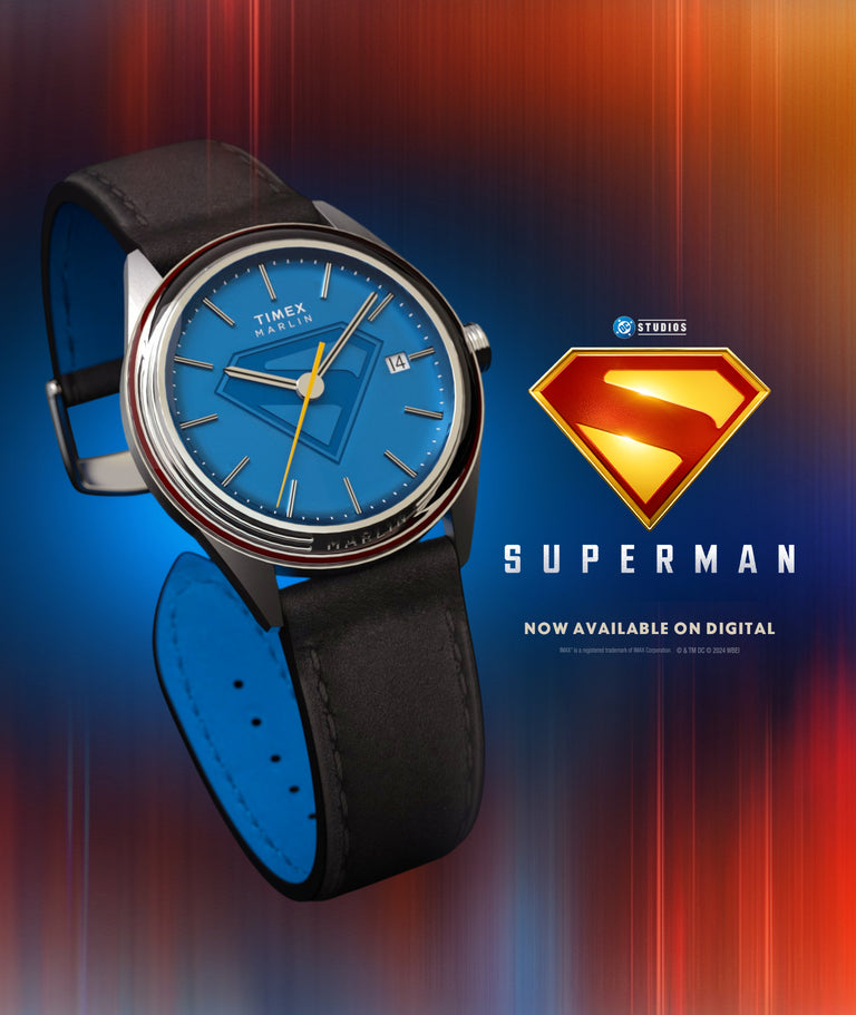 Timex x Superman Marlin® Jet Automatic watch with a blue dial featuring the iconic Superman “S” shield, yellow seconds hand, date window at 3 o’clock, and black leather strap, displayed against a red and blue gradient background with the Superman logo and promotional text.