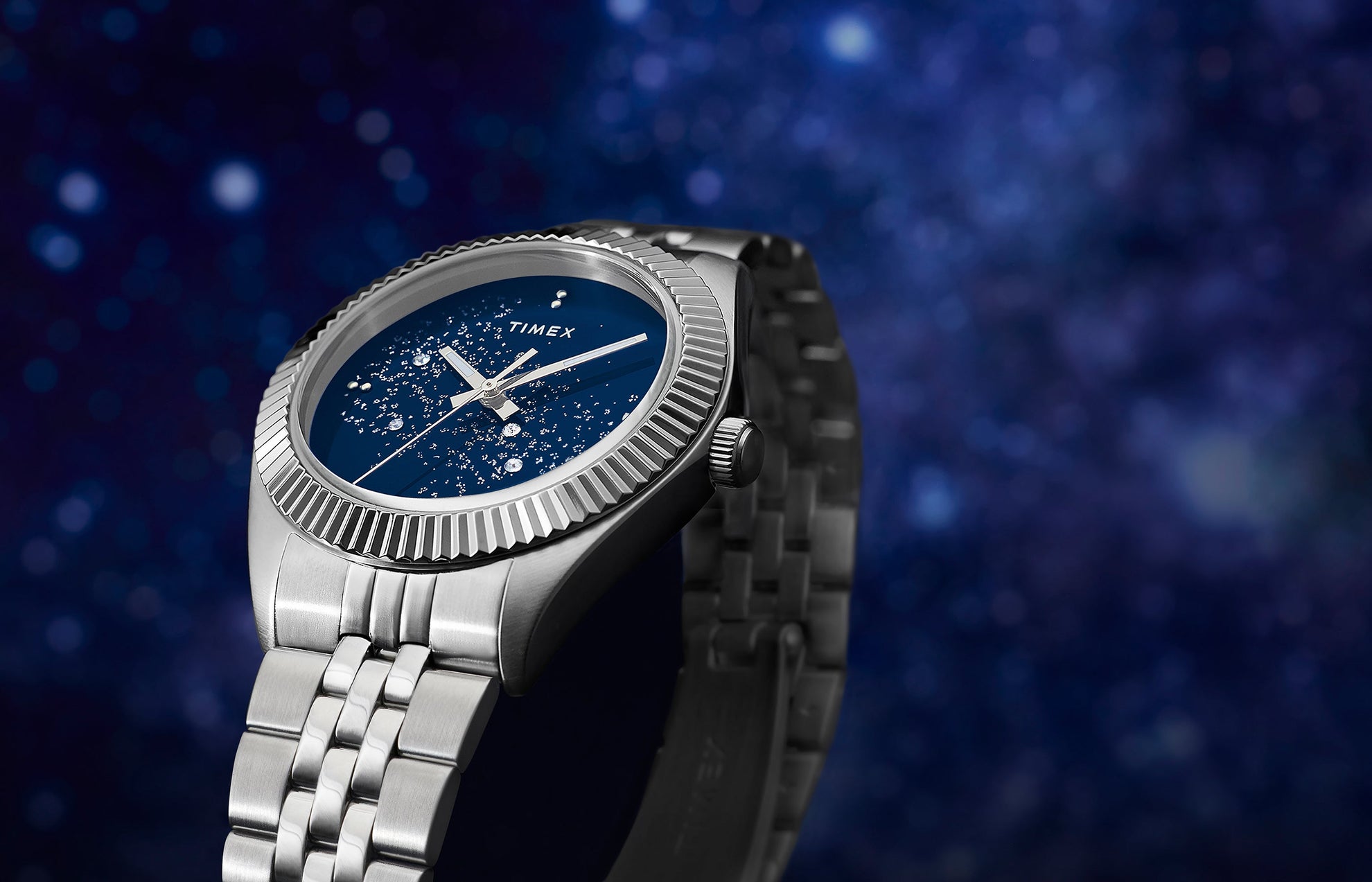 Timex Legacy watch with a stainless-steel case and bracelet featuring a deep blue dial with sparkling crystal accents that resemble a starry night sky.