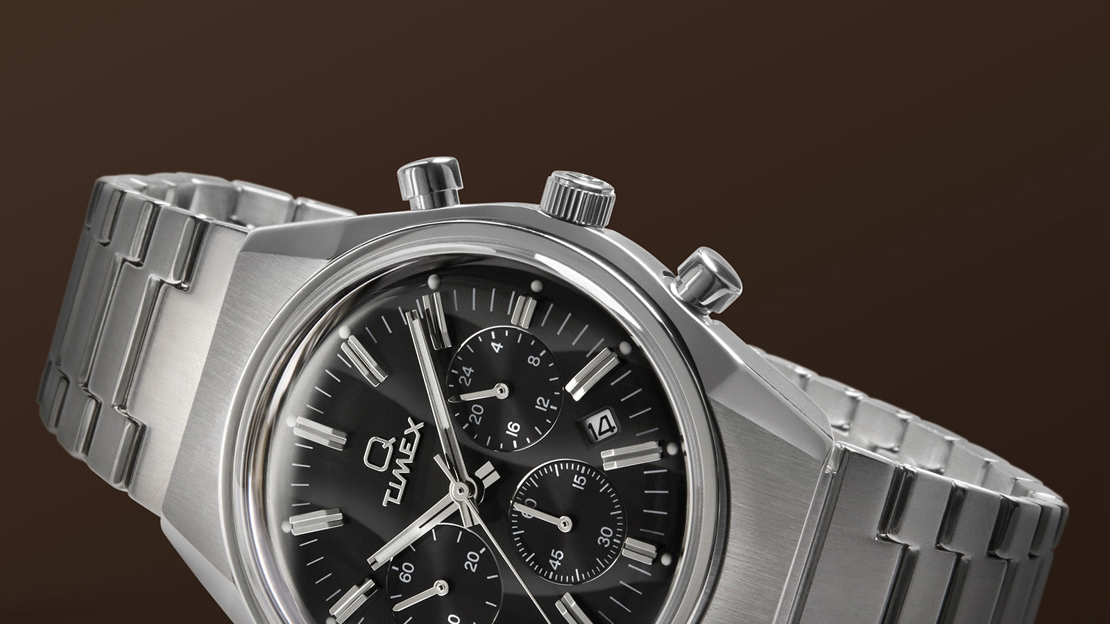 Side profile of the Q Timex Falcon Eye Chronograph in brushed stainless steel showing crown, pushers, and integrated bracelet links.