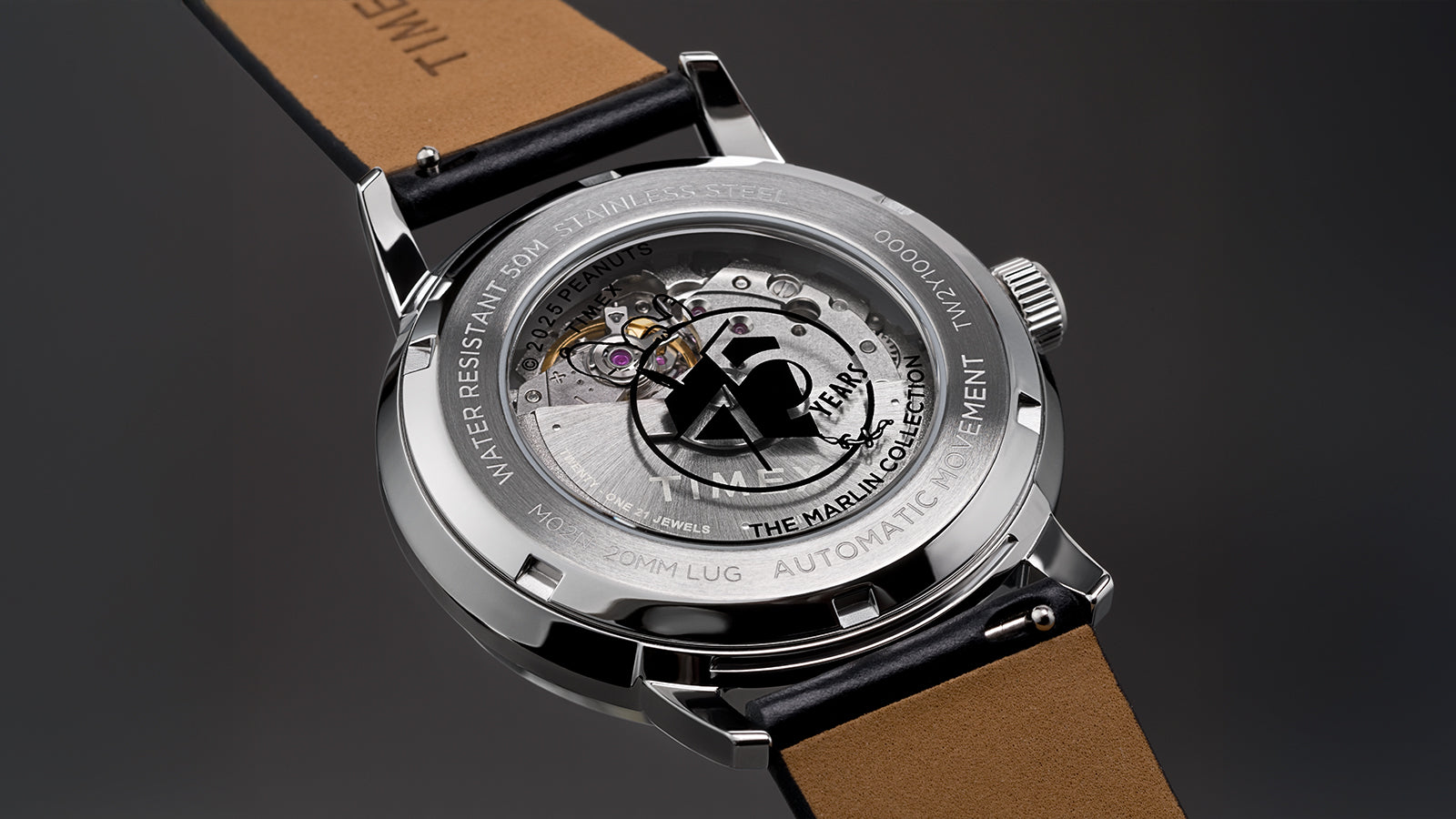 Close-up of the Timex x Peanuts® Marlin® Automatic 75th Anniversary Edition transparent caseback, revealing the automatic movement with the “75 Years” Peanuts logo etched on the rotor. Stainless steel markings and water-resistance specifications are engraved around the rim.