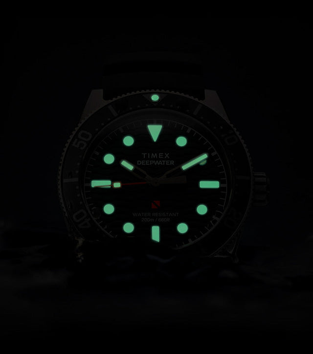 Timex Deepwater Reef 200 watch glowing in darkness, with bright green lume on the hands and hour markers, emphasizing superior underwater visibility.