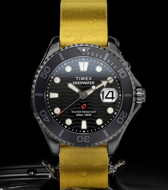 Timex Deepwater Meridian 200 dive watch with yellow silicone strap and black dial emerging from dark water, showcasing its 200-meter water resistance and wave-pattern texture.
