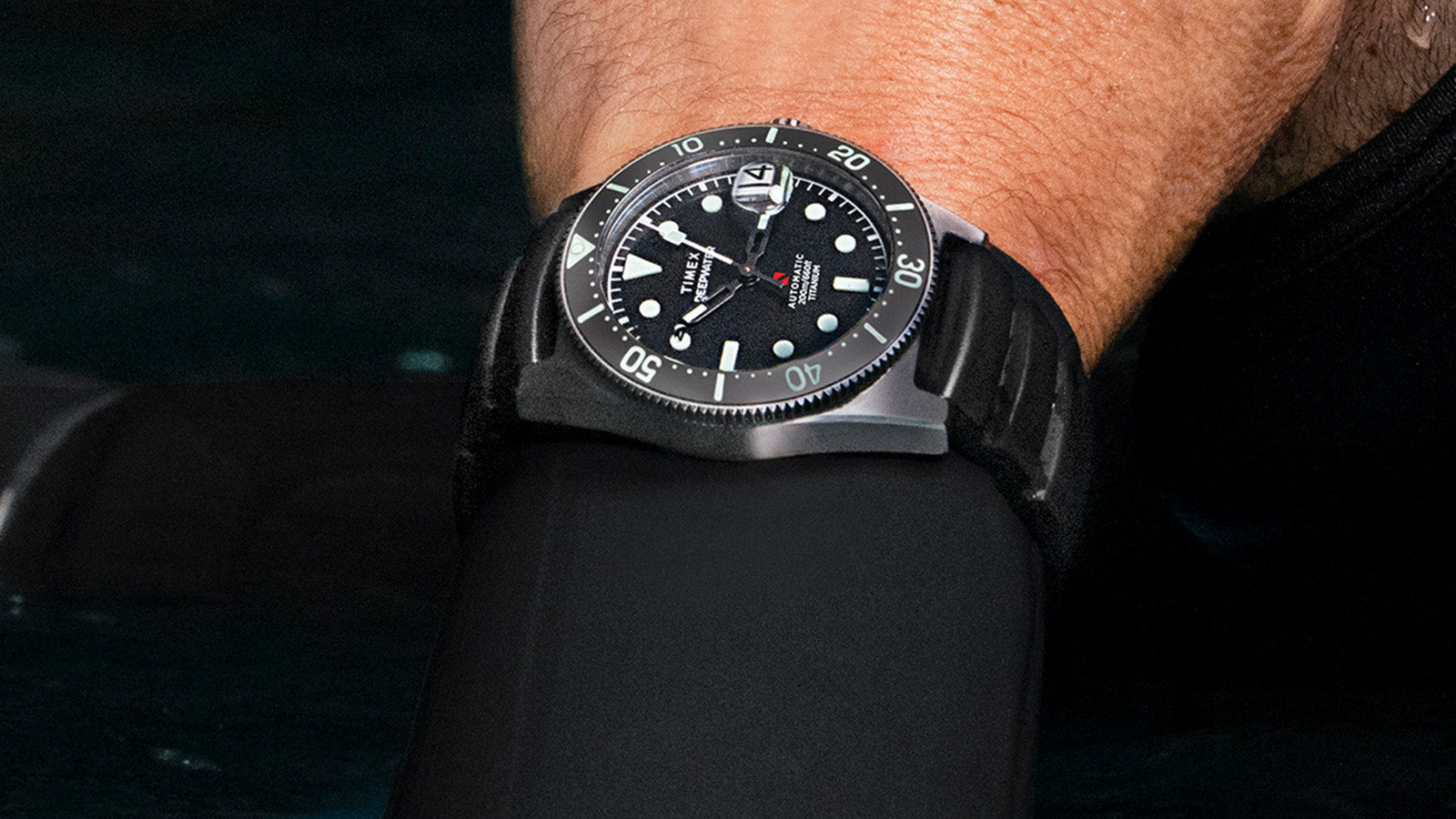 Close-up of diver’s wrist wearing the Timex Deepwater Reef 200 Titanium Automatic, displaying the rotating bezel, luminous dial, and bold minute markers.