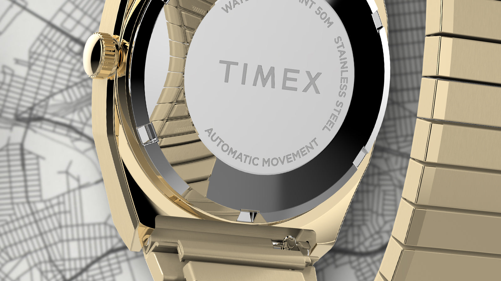 Close-up of the Timex® Automatic 1983 E Line Reissue gold-tone caseback showing engraved TIMEX logo, automatic movement marking, and polished finish.