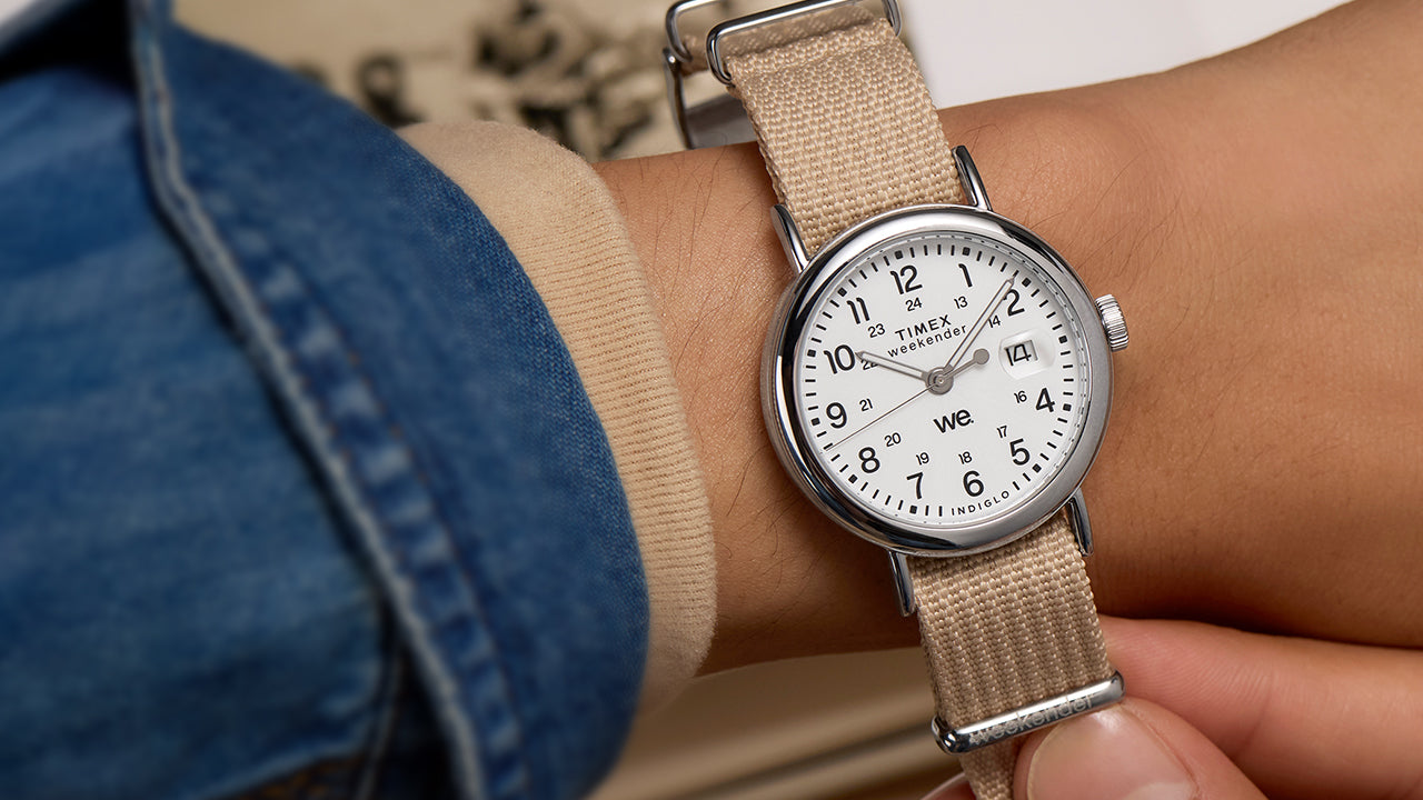 Timex Weekender watch with beige strap worn on a wrist, styled casually with a denim jacket sleeve.