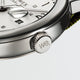 Close-up of the Timex Weekender’s crown engraved with “we.” next to the white dial and date window.