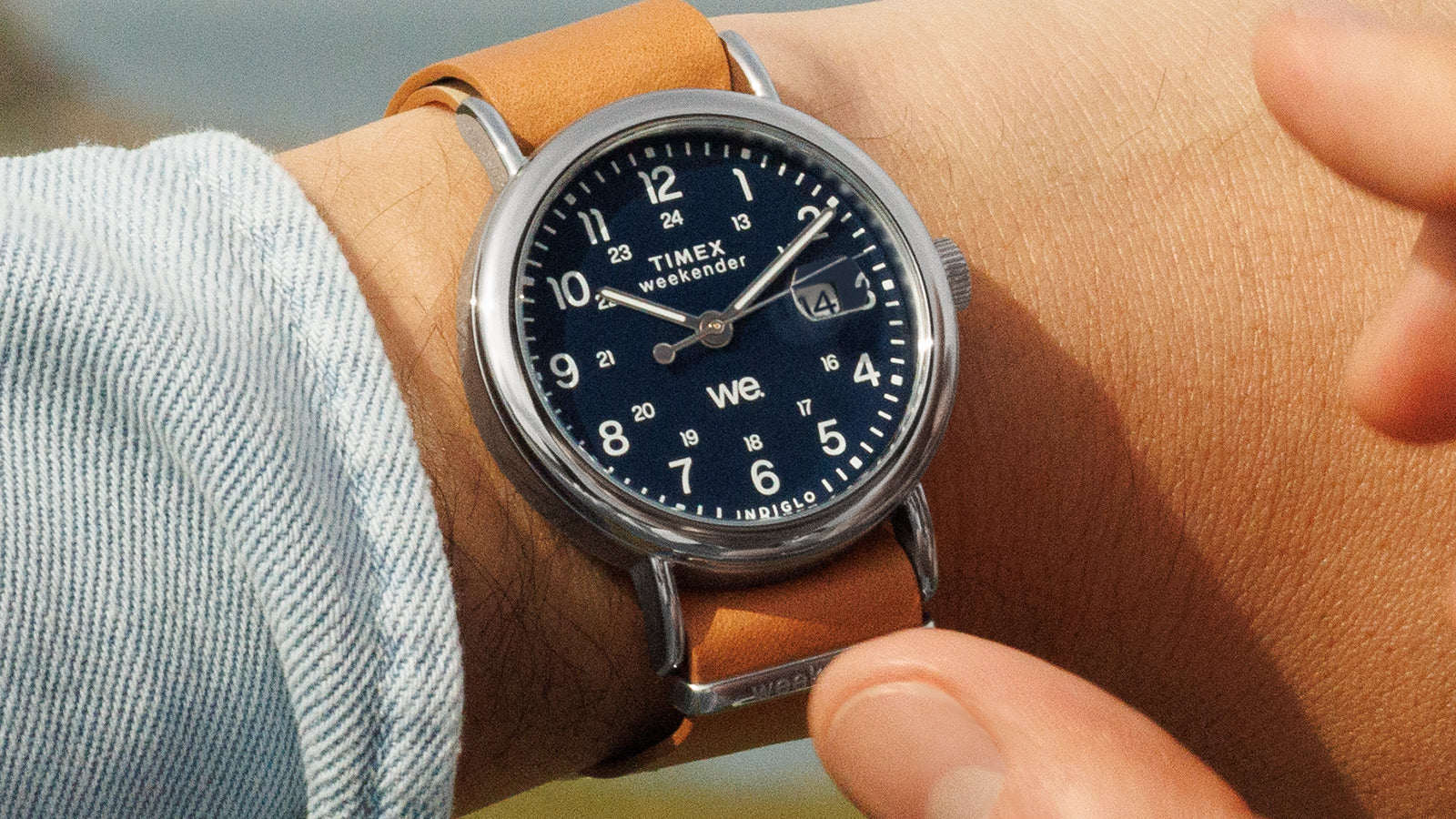 Timex Weekender watch with blue dial and brown leather strap on wrist outdoors, captured in natural light.