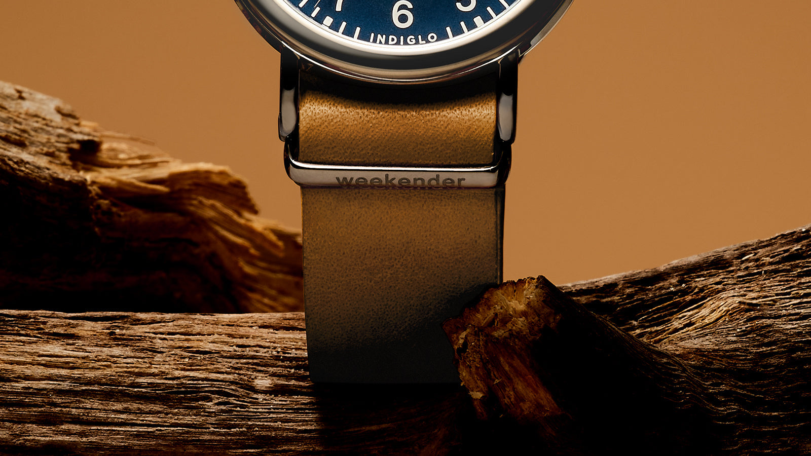 Close-up of the brown leather strap of the Timex Weekender watch with engraved “weekender” branding on the silver-tone loop.
