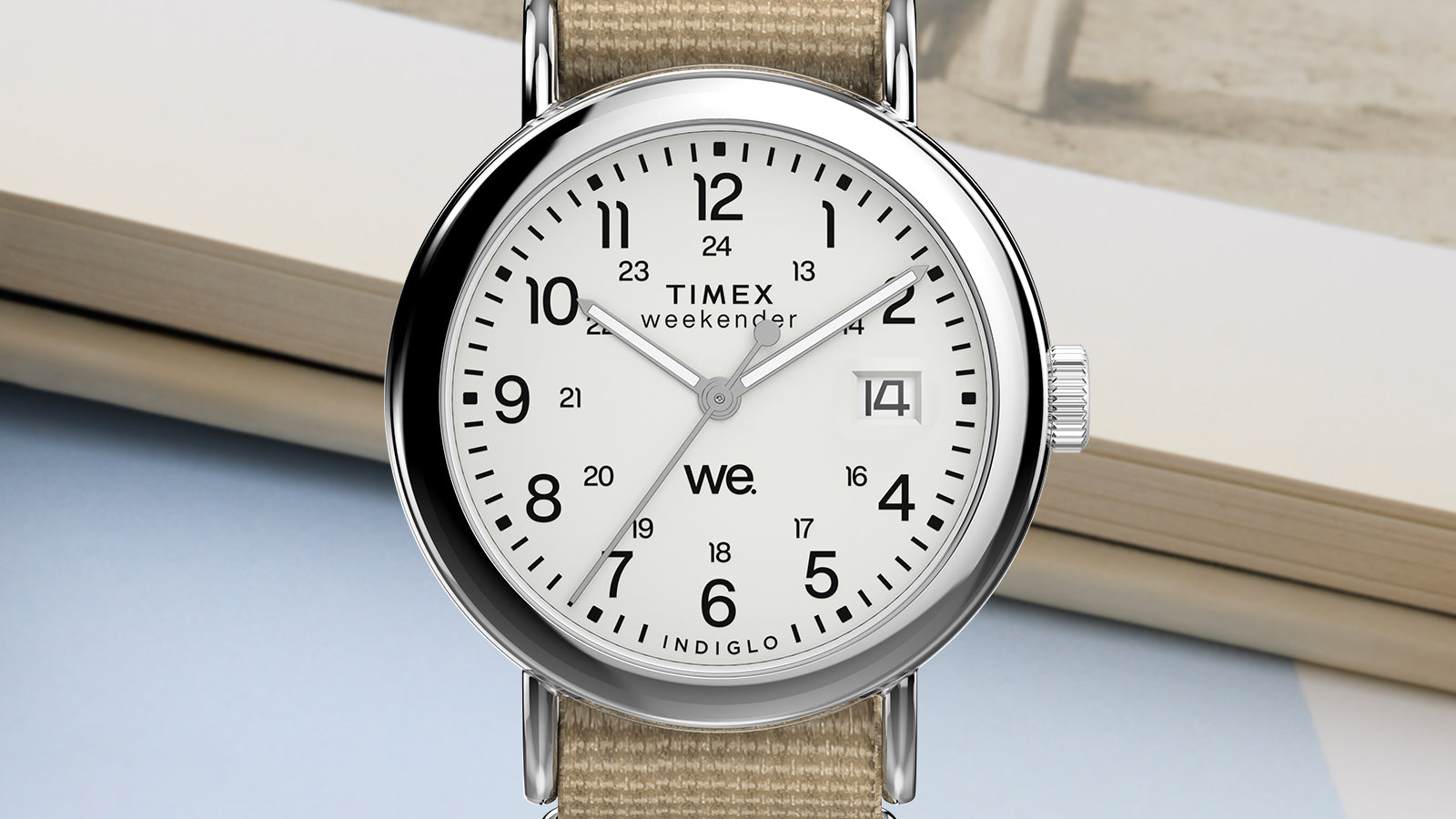 Close-up of the Timex Weekender watch face with black numerals, silver-tone case, and beige strap, with a visible date window.