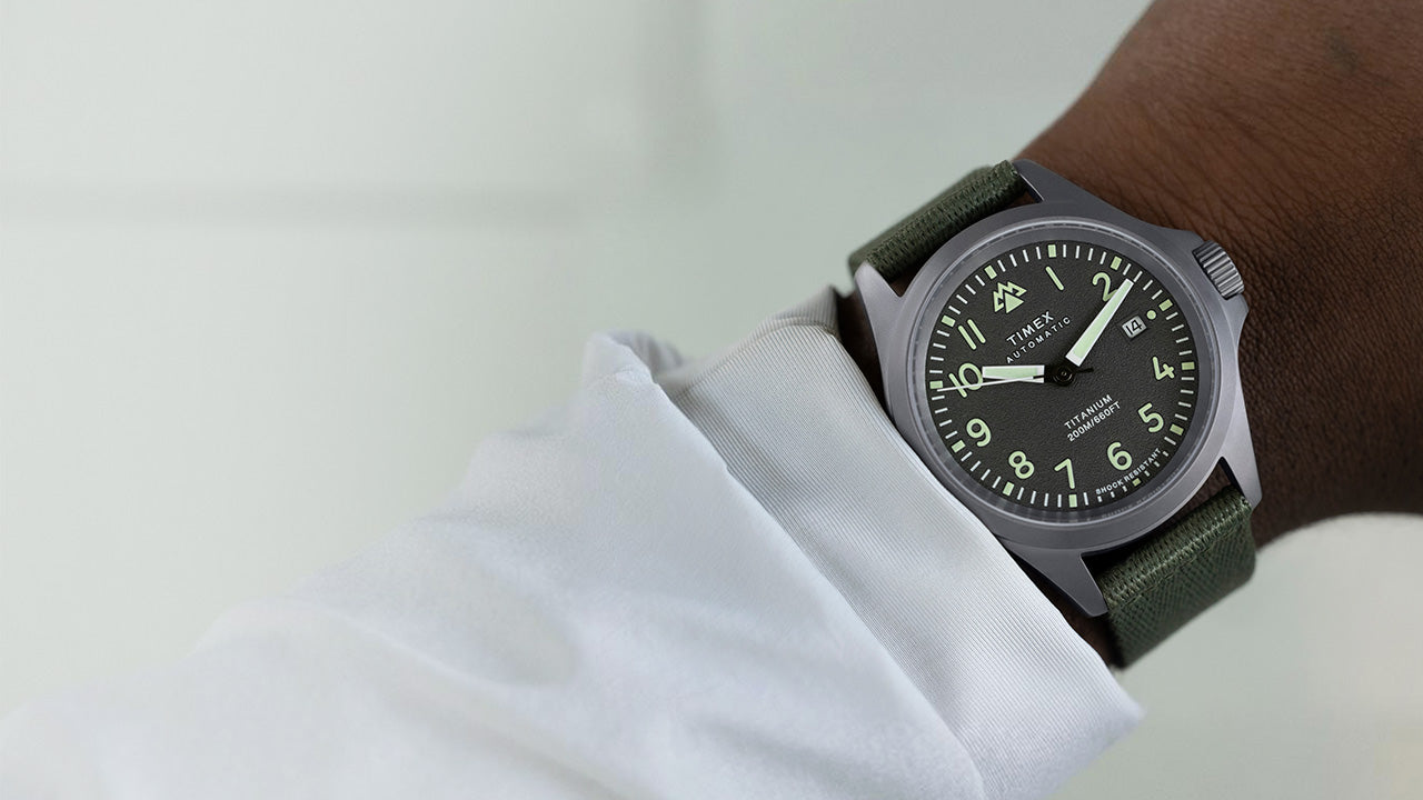 The Timex Expedition North Titanium Automatic watch worn on the wrist, featuring a rugged titanium case, luminous black dial, and green strap for an outdoors-ready look.
