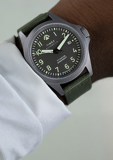 The Timex Expedition North Titanium Automatic watch worn on the wrist, featuring a rugged titanium case, luminous black dial, and green strap for an outdoors-ready look.