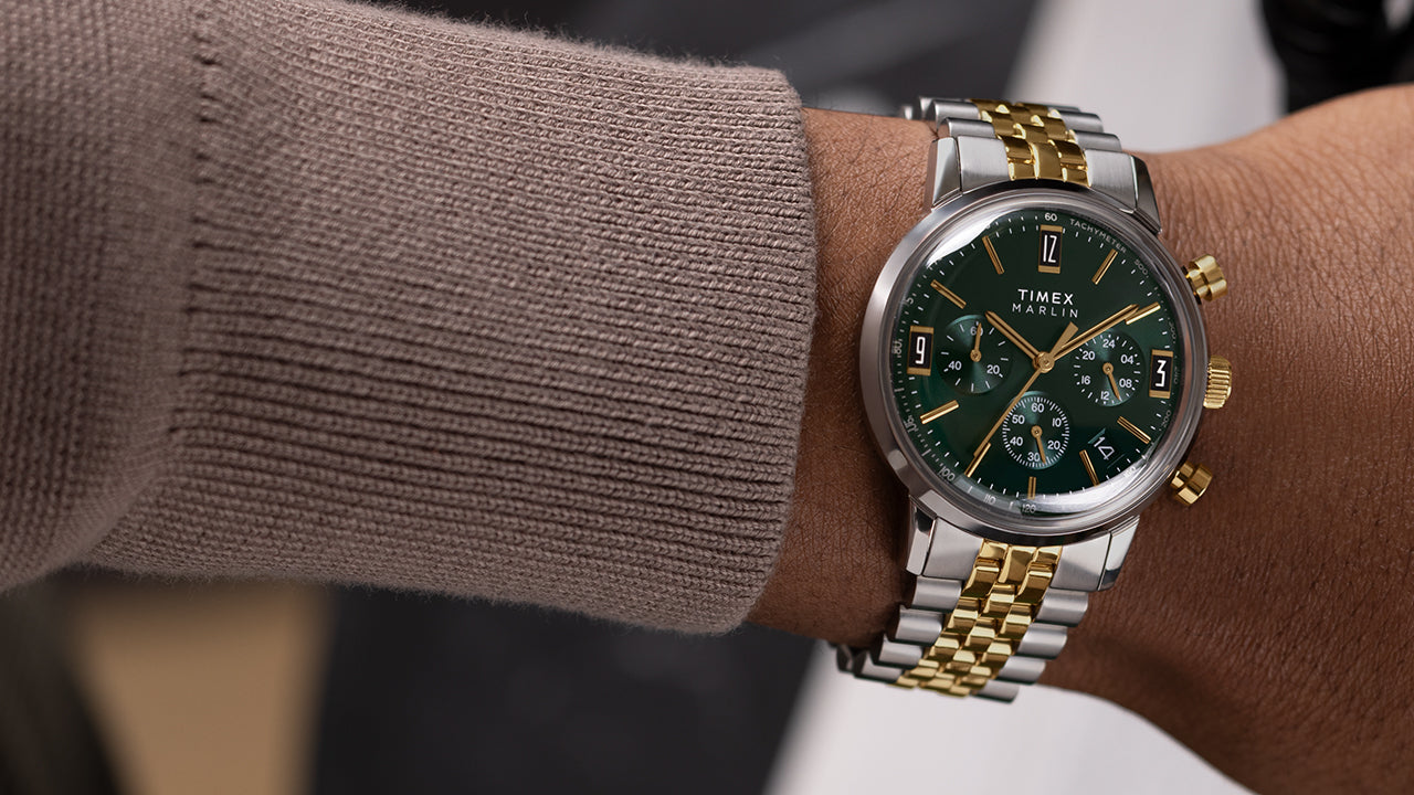 Person wearing Timex Marlin Chronograph Tachymeter with green dial and two-tone bracelet, styled with a taupe sweater sleeve.
