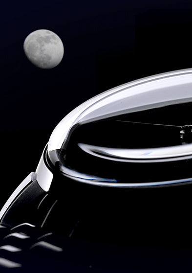 Close-up of the Timex Marlin Moon Phase Multifunction showing domed crystal and moonlit reflection against a night sky background with a visible moon.