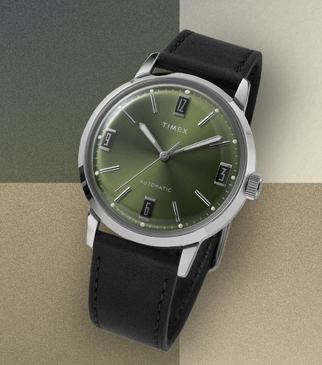 Timex Marlin Automatic watch with green sunray dial and black leather strap displayed on a beige and olive color block background.