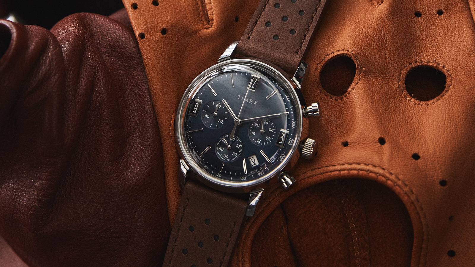 Timex Marlin Chronograph Tachymeter watch on brown leather driving gloves highlighting its vintage-inspired racing aesthetic.
