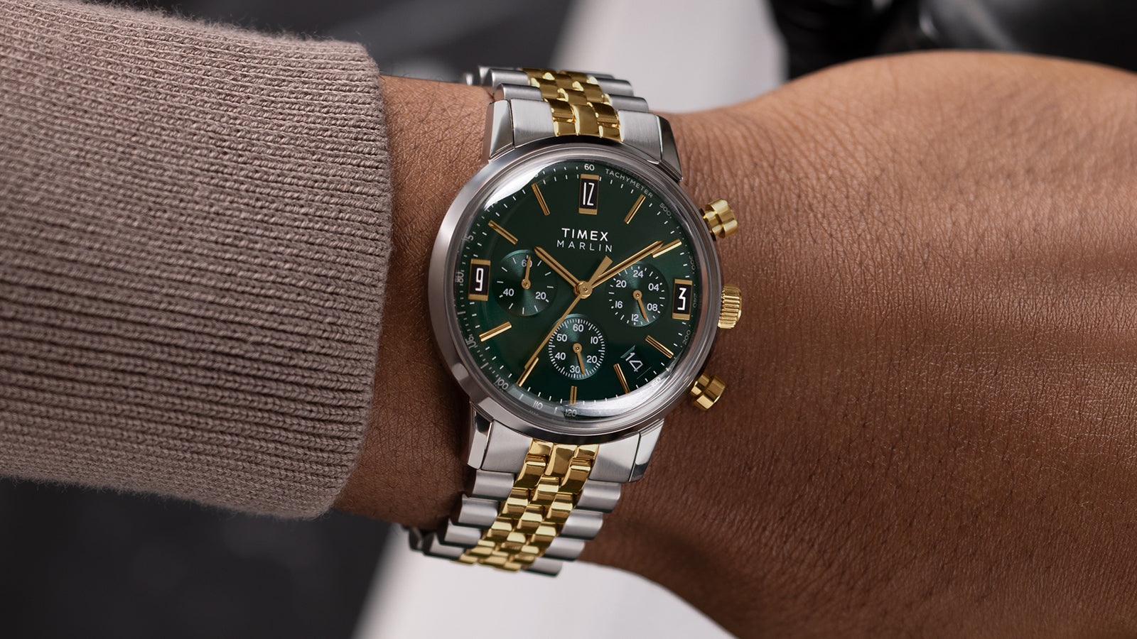 Timex Marlin Chronograph Tachymeter with green dial and two-tone bracelet worn on wrist, highlighting gold pushers and polished finish.
