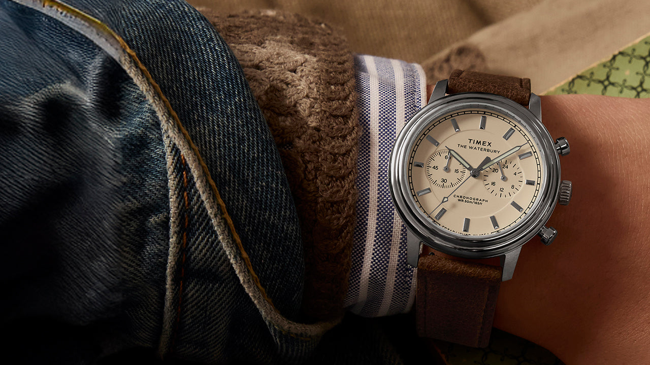 Timex Waterbury Metropolitan Chronograph on wrist highlighting cream chronograph dial and stainless steel case, styled with casual layered clothing.