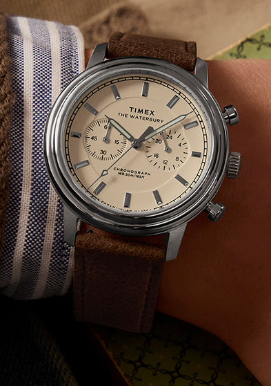 Timex Waterbury Metropolitan Chronograph on wrist highlighting cream chronograph dial and stainless steel case, styled with casual layered clothing.