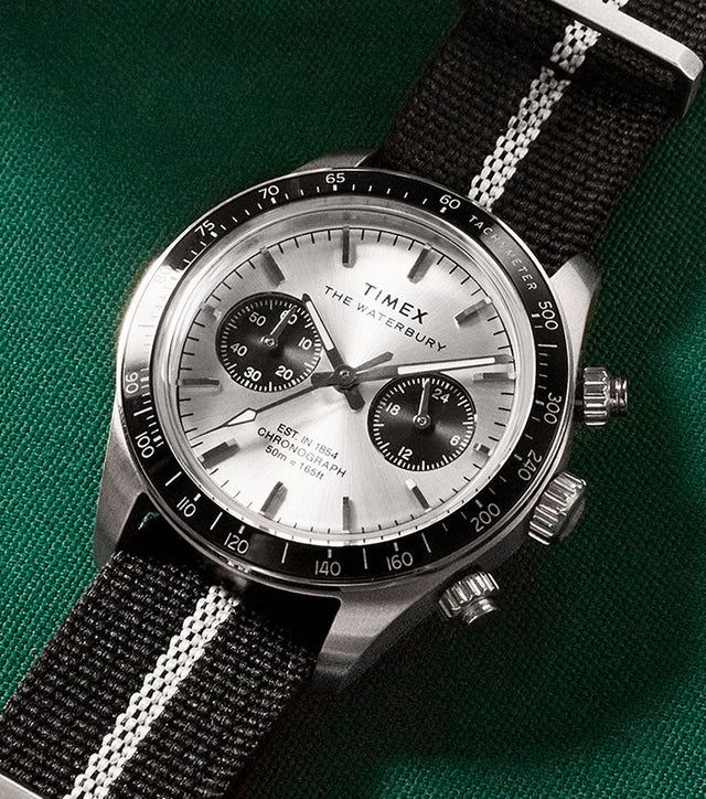Timex Waterbury Heritage Chronograph with brushed silver dial and black sub-dials resting on a green billiards table.