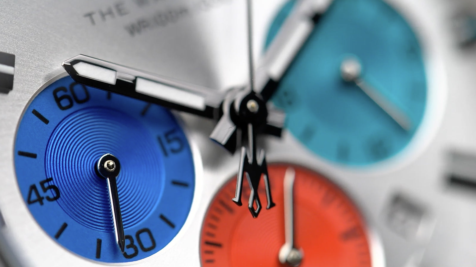 Close-up of the Timex Waterbury Chronograph’s blue, red, and teal sub-dials with textured concentric patterns and polished chronograph hands.