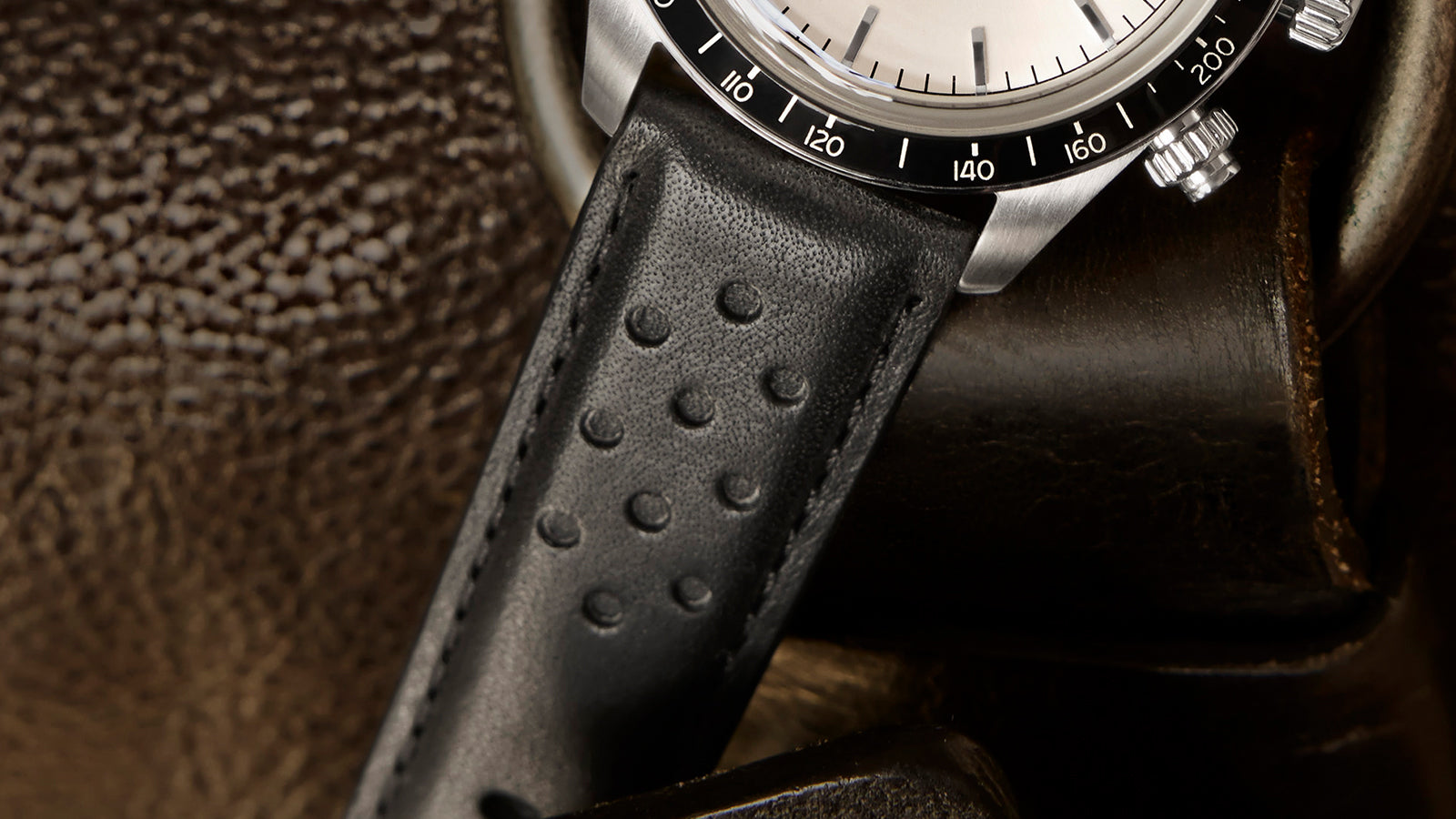 Detail shot of the Timex Waterbury Heritage Chronograph black perforated leather strap showing fine stitching and grain texture.