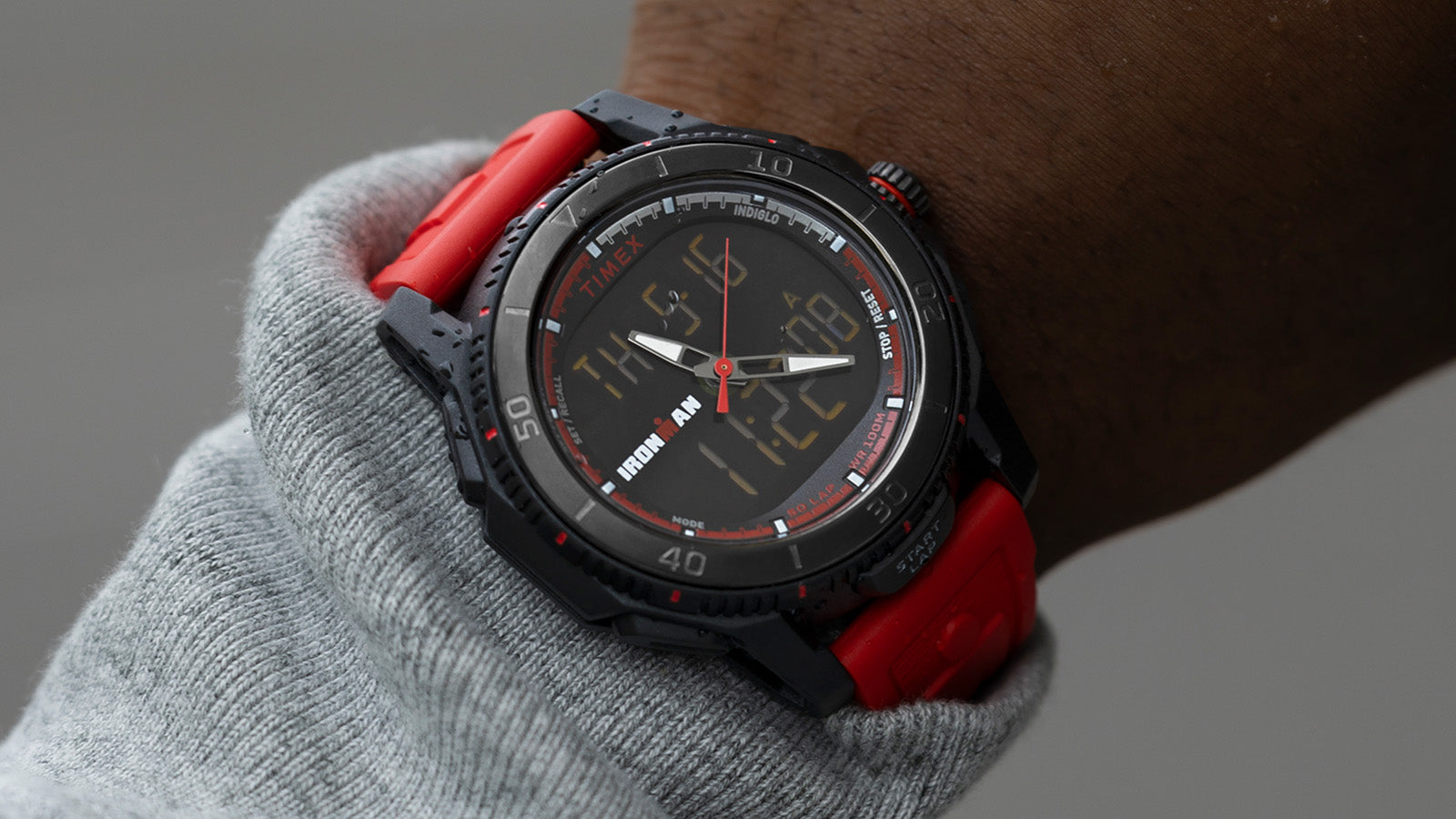 Side view of the TIMEX® IRONMAN® Adrenaline Ana-Digi watch with red strap, emphasizing the durable black case and rotating bezel.