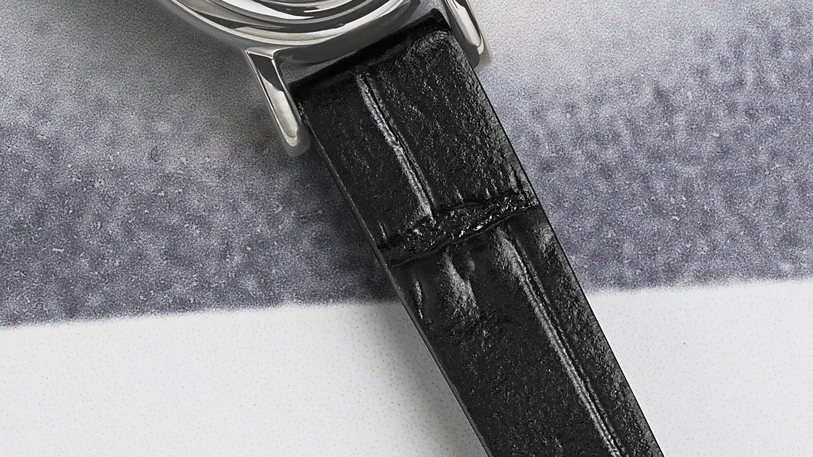 Close-up of the black crocodile-pattern leather strap attached to the silver-tone oval case of the TIMEX® Cavatina watch.